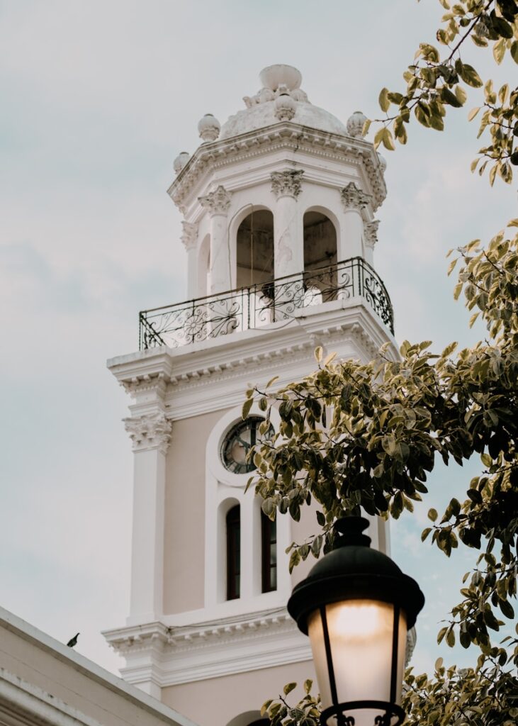 a white clock tower with a light on top of it